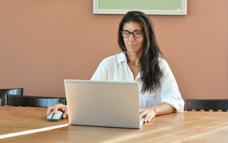 A woman wearing glasses typing on a laptop
