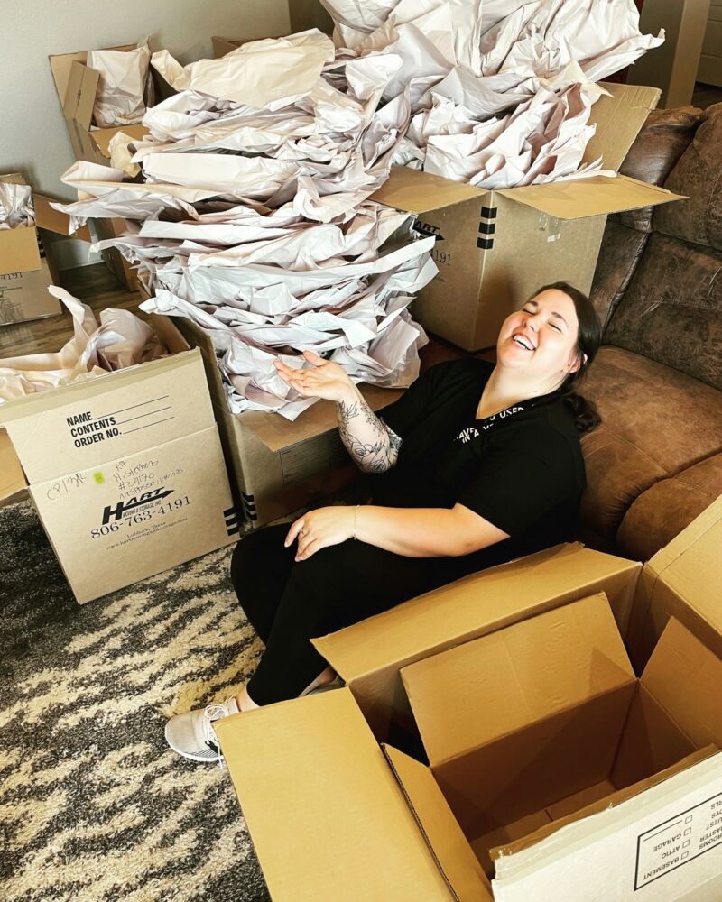 A woman laughing while packing moving boxes at home