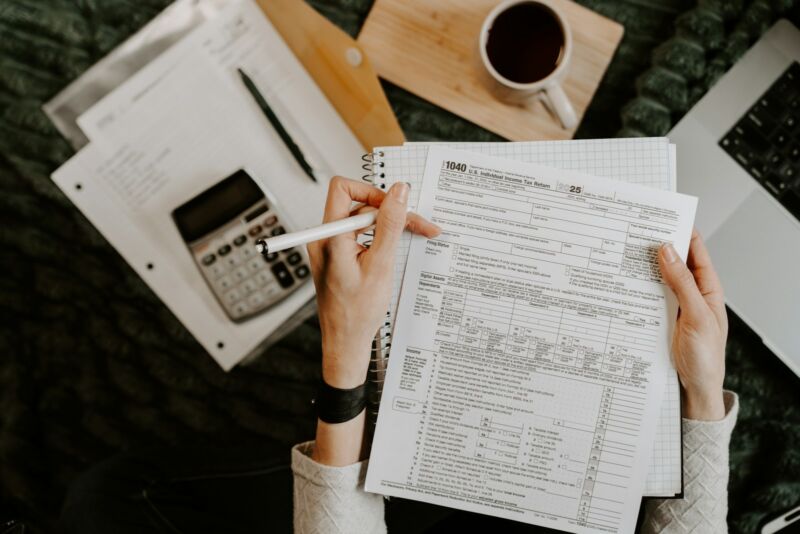 Hands reviewing paperwork with a calculator and laptop