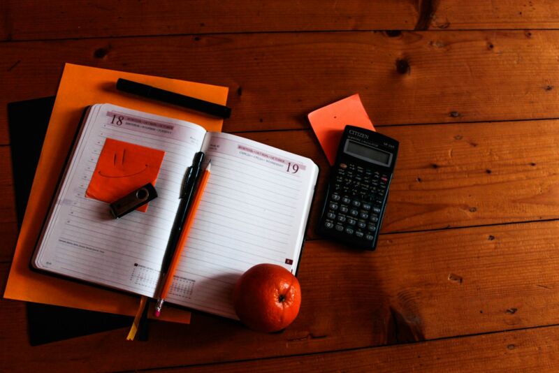 A calculator and open notebook on a wooden table