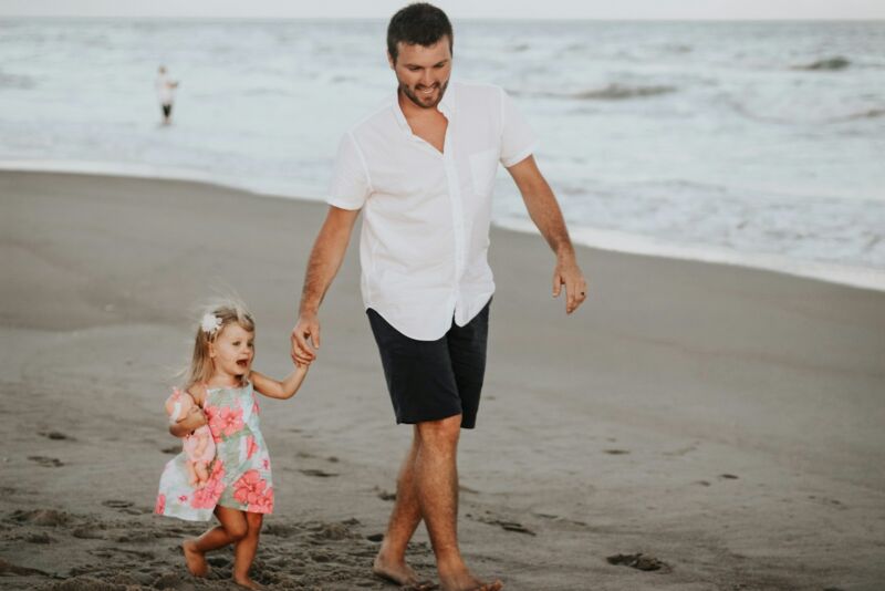 A father carrying his daughter along the coast