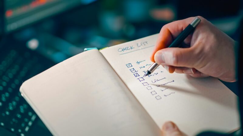 A hand writing a checklist in a notebook