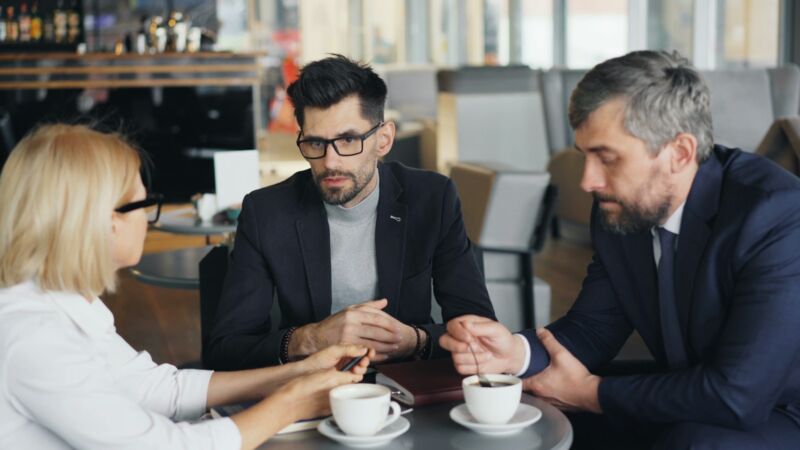 Three adults in calm conversation around a table
