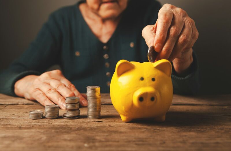 Hands dropping a coin into a piggy bank