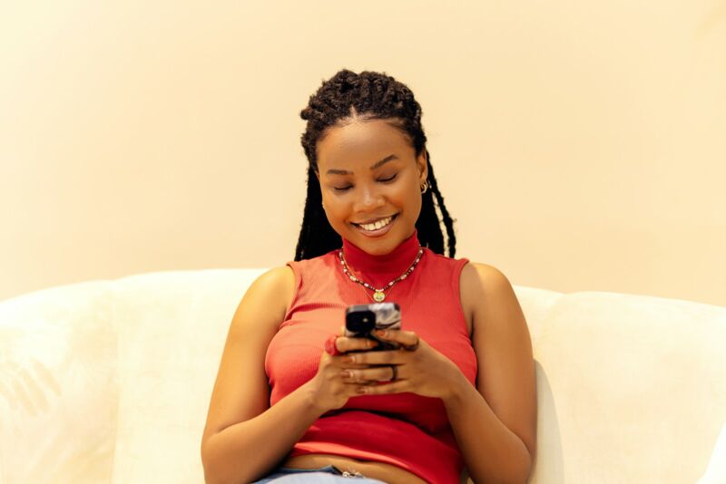 A woman at home on a couch looking at her phone