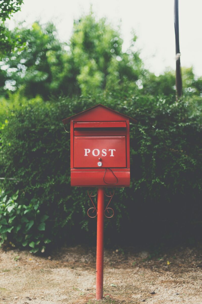 A red mailbox surrounded by green leaves