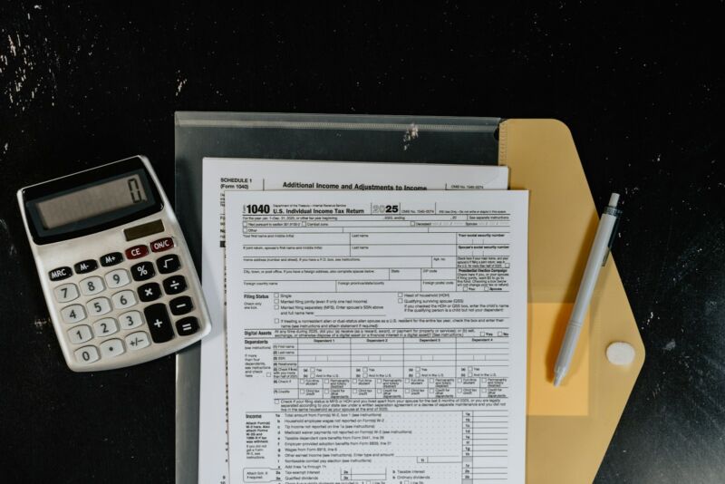 Tax forms, a calculator and a pen on a desk