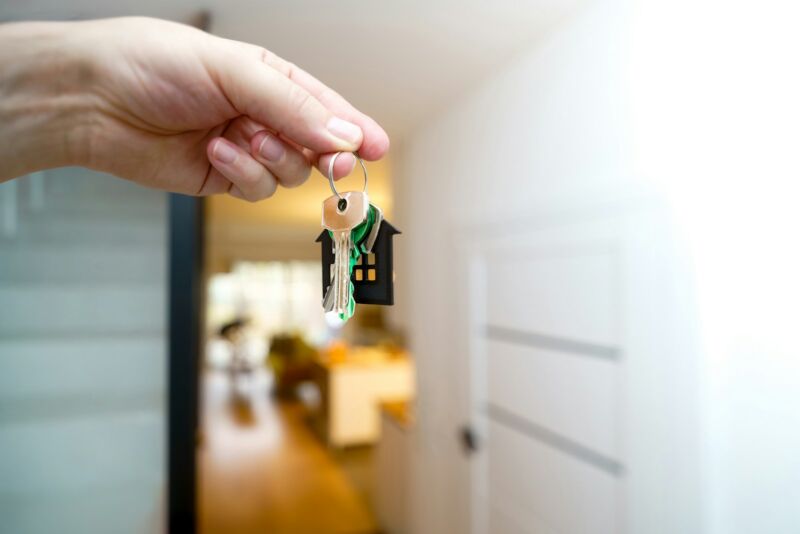 A hand holding house keys at a front door