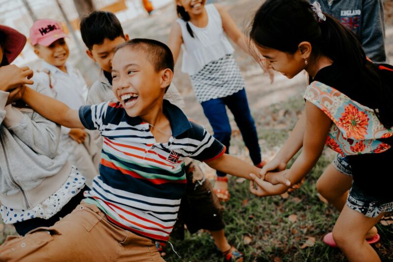 Children laughing and playing on a grassy field