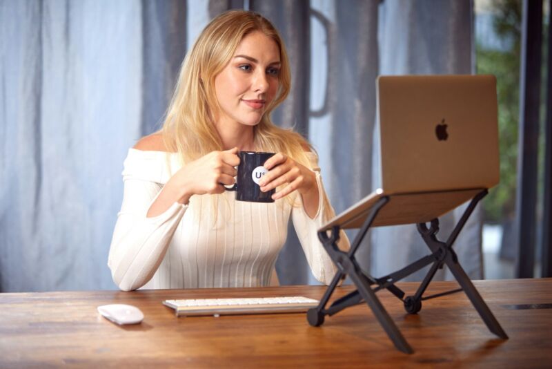 A woman working at a kitchen table with a laptop and coffee