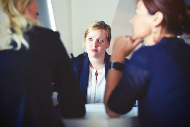 Three women talking calmly around an office table
