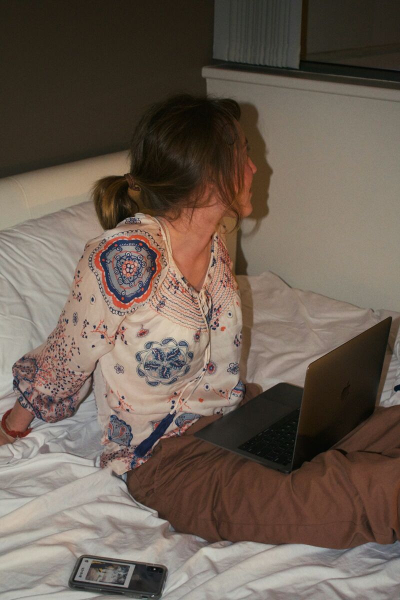 A woman on a laptop in a dim bedroom at night