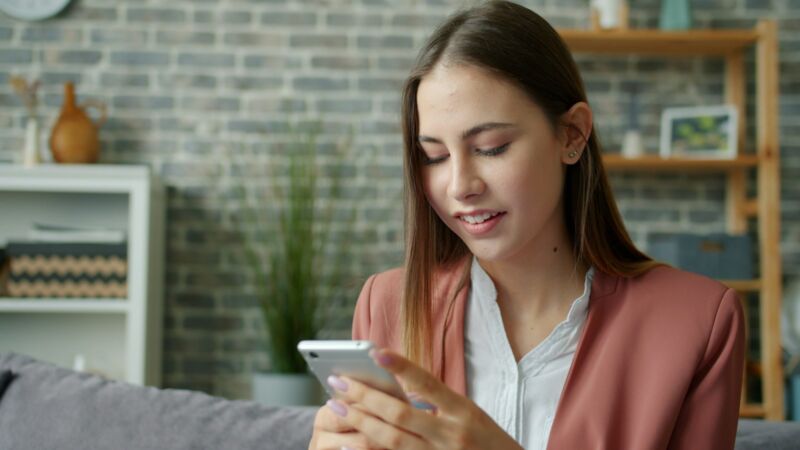 A young woman relaxing on a couch, looking at her phone
