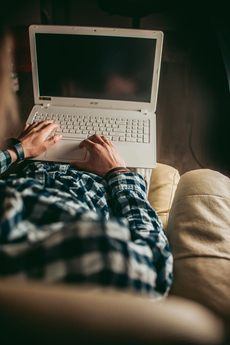 A man relaxing on a couch using his laptop