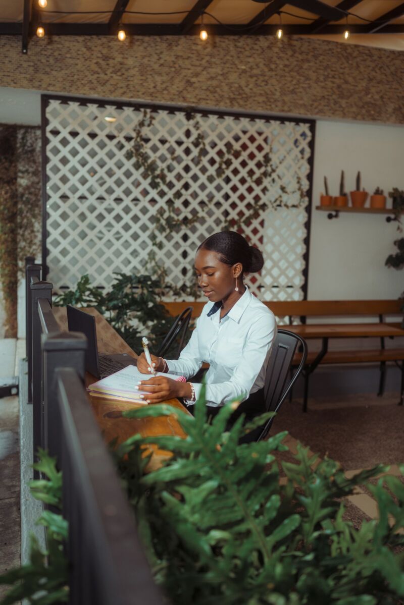 A woman writing a plan in a notebook at a cafe