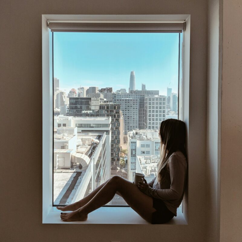 A woman calmly gazing out a sunny window