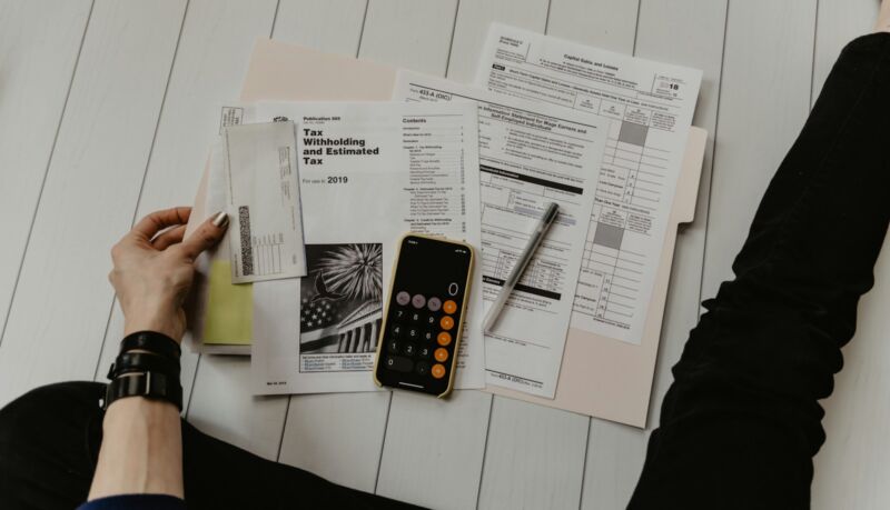 A woman holding budget papers beside a calculator
