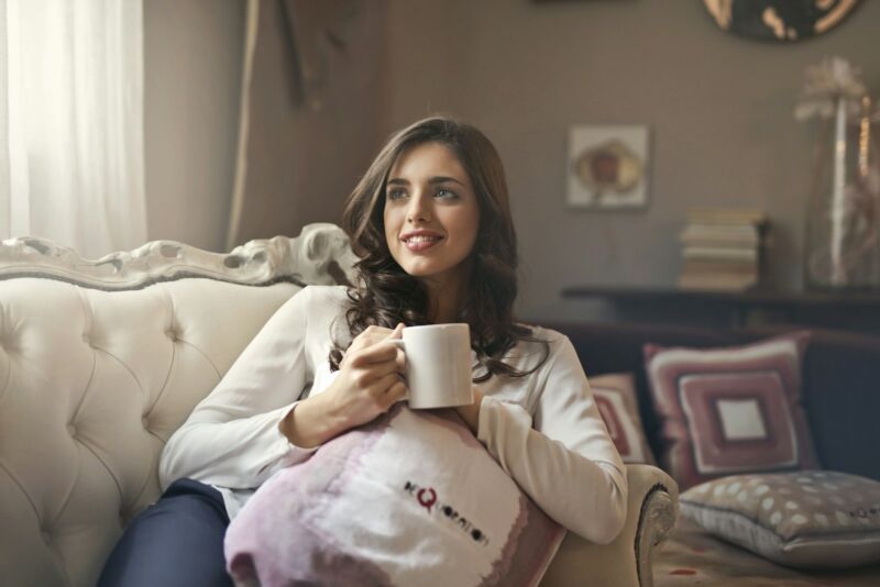 A woman relaxing on a sofa holding a warm mug